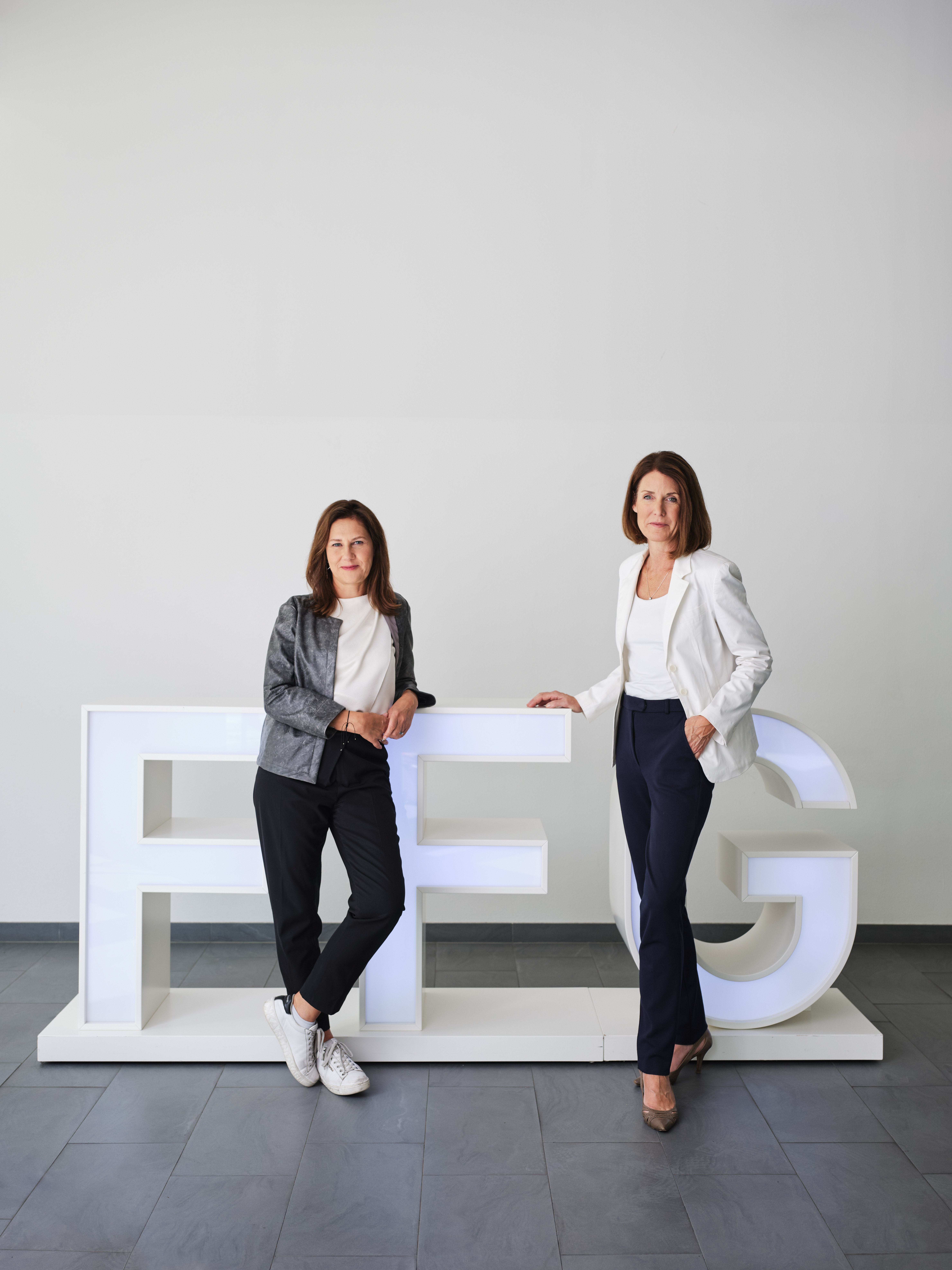Two woman standing in front of FGG logo